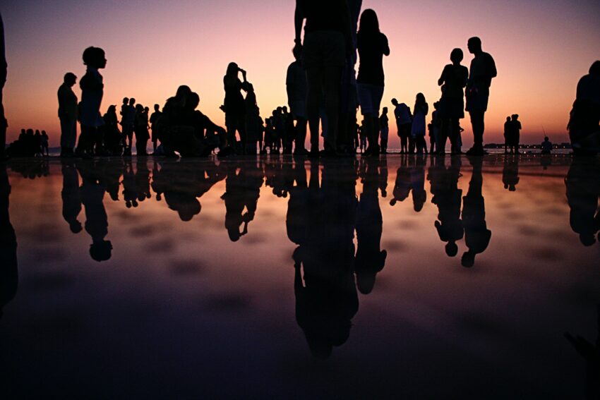 Groep mensen die samenkomen bij zonsondergang op strand