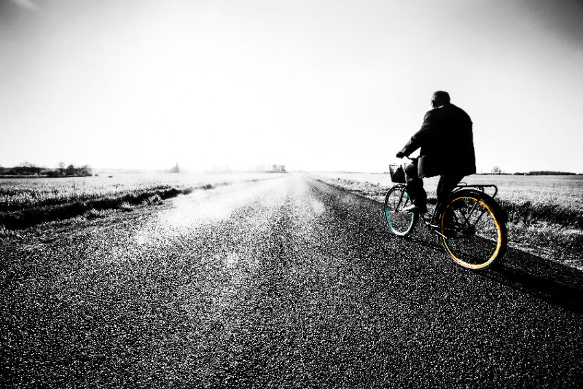 oude man op fiets door weg in weiland